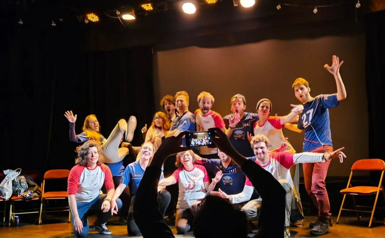 Troupe de l'Atelier Off posant sur scène dans une ambiance conviviale